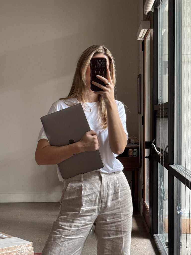 Woman holding a laptop, dressed in a fashionable business casual outfit for women, ideal for office work.