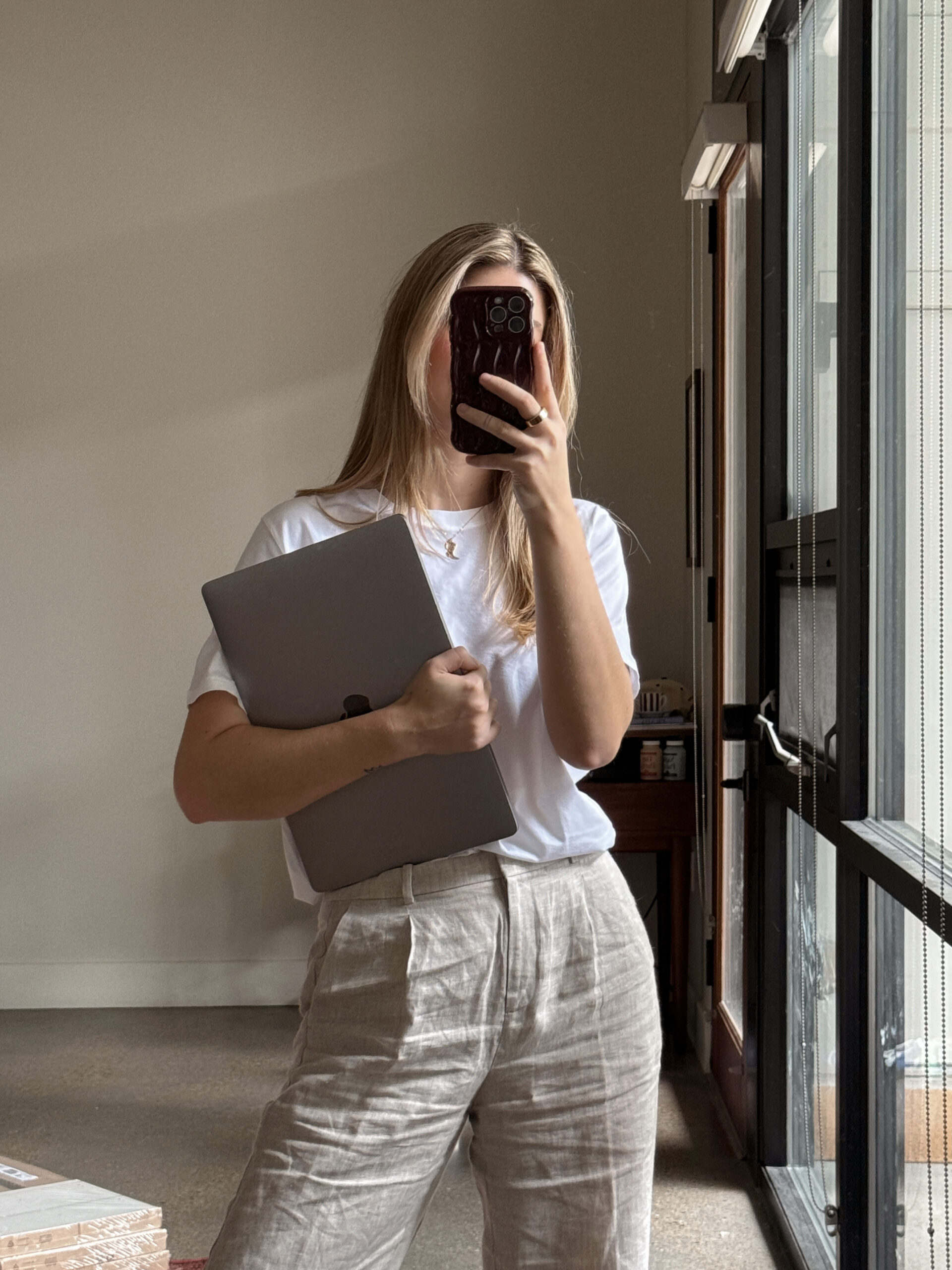 Woman holding a laptop, dressed in a fashionable business casual outfit for women, ideal for office work.