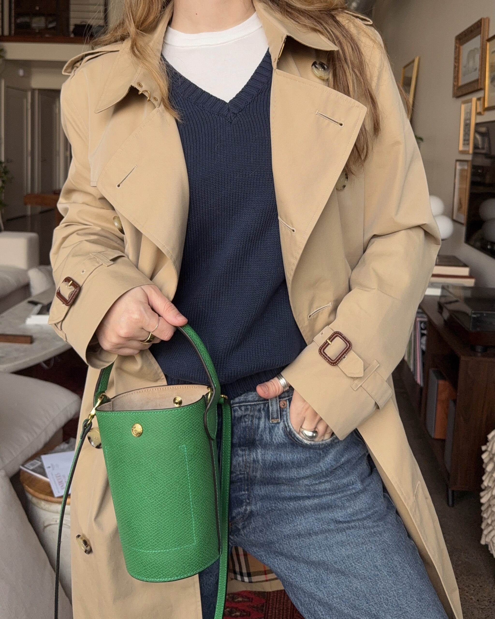 Chic winter fashion look consisting of a sweater vest layering look done in neutral materials and accessories like gold jewelry, along with boots.